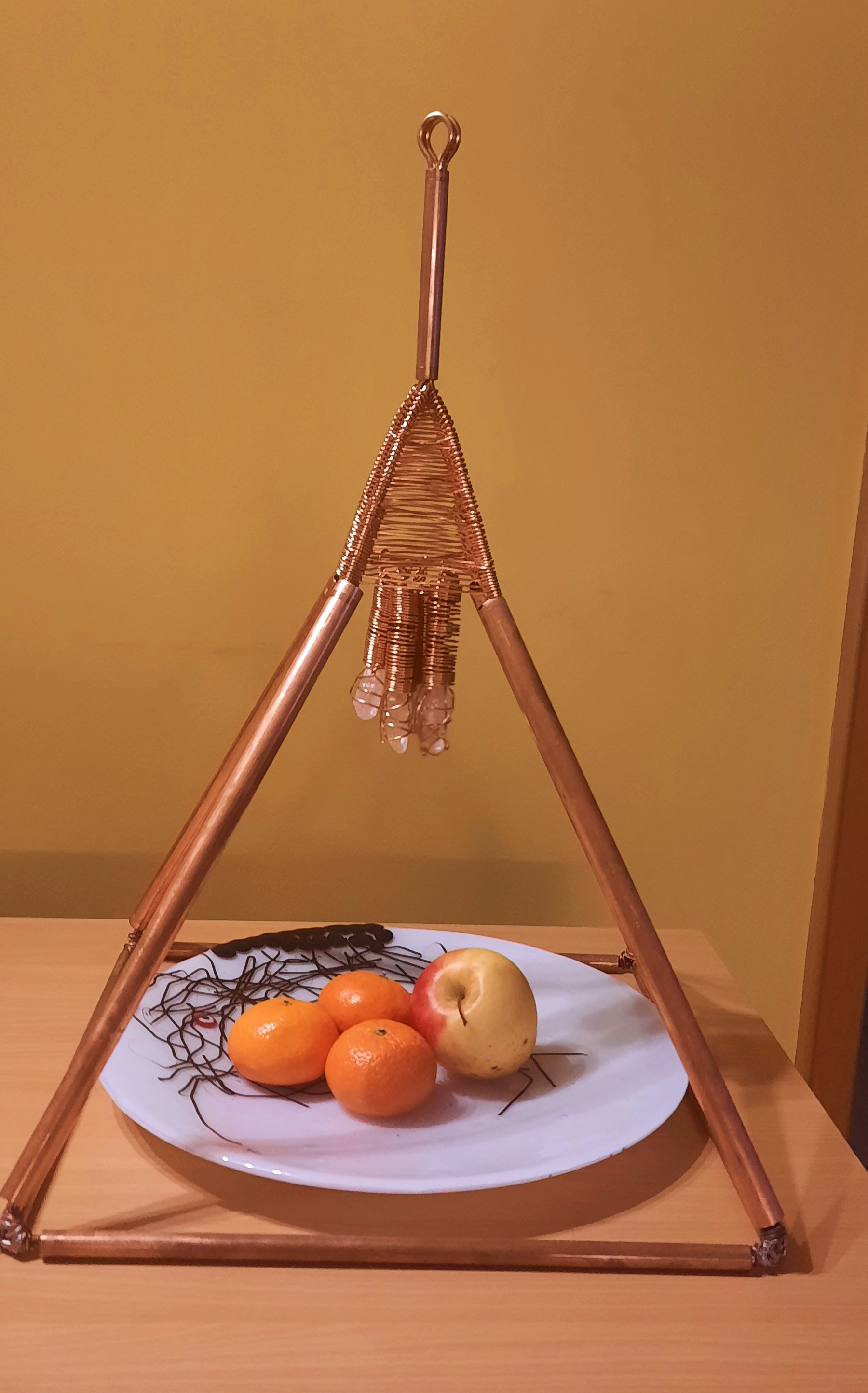 Tisch-Pyramide aus Kupfer über einem Teller mit Obst